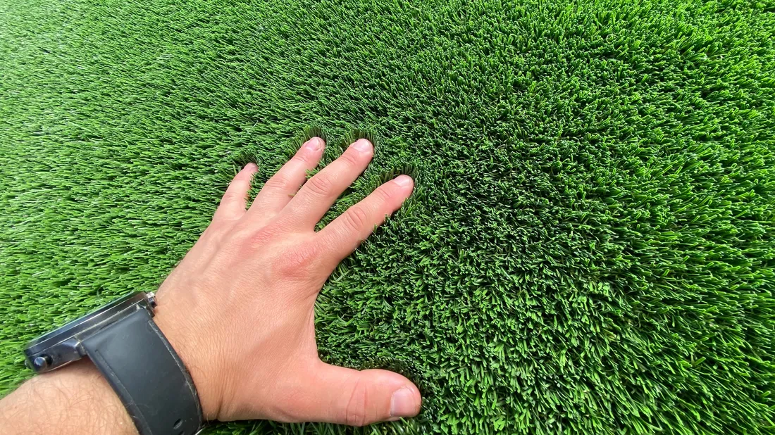 Hand checking the pile density of artificial grass